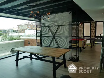 Spacious industrial-style loft with exposed brick walls and modern lighting, featuring a large dining table and an open floor plan.