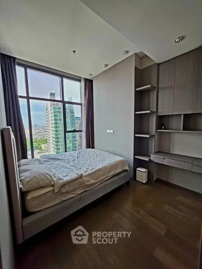 Modern bedroom with large window offering city view, featuring sleek built-in storage and cozy bed.
