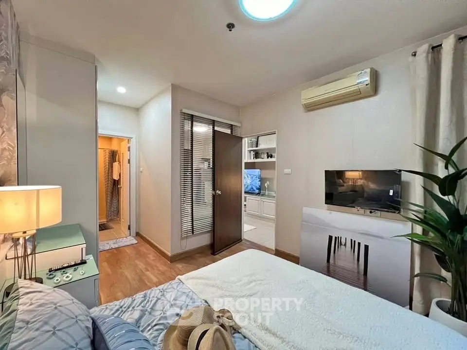 Cozy bedroom with modern decor and air conditioning, featuring a view into a stylish living area.
