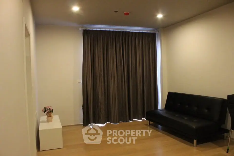 Modern living room with sleek black sofa and elegant curtains in a minimalist design.