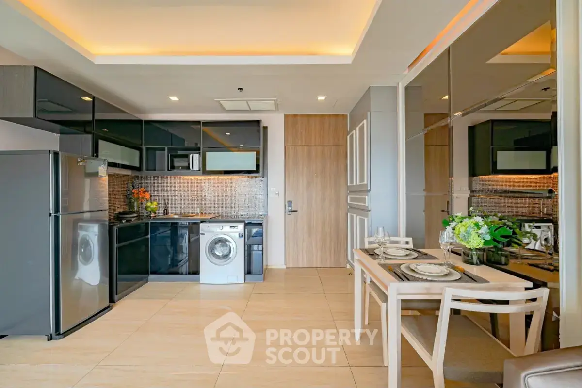 Modern kitchen with sleek appliances and dining area in open layout apartment.