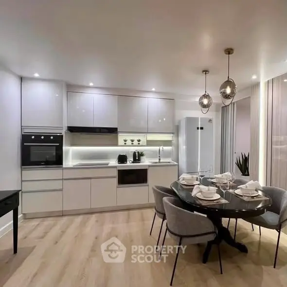 Modern kitchen with sleek cabinetry, dining area, and contemporary lighting in a stylish apartment.