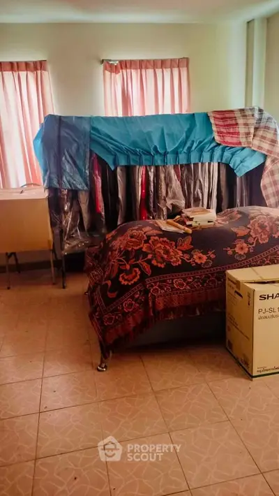 Cozy bedroom with natural light and tiled flooring, featuring a bed and storage boxes.