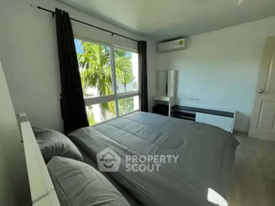 Bright bedroom with large window and modern furnishings, featuring a serene view of palm trees.