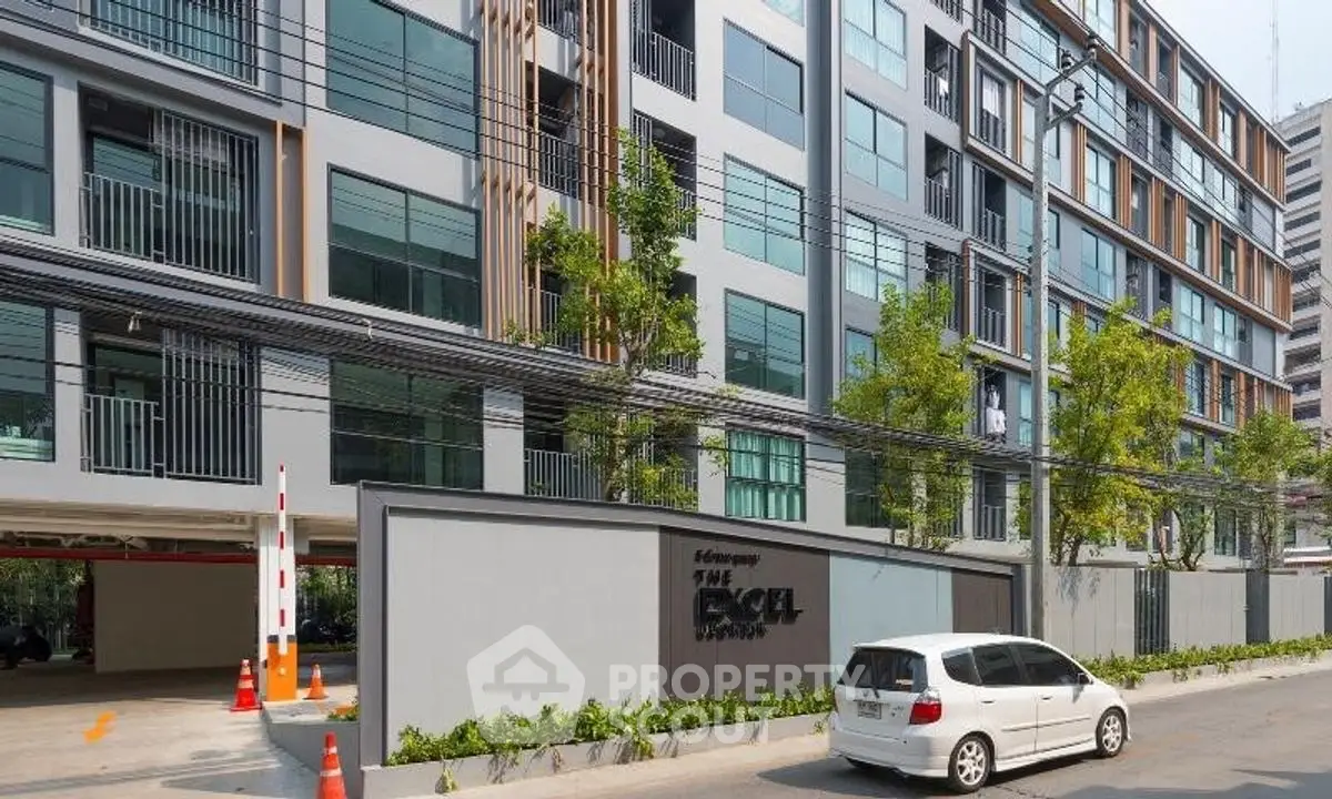 Modern residential building exterior with parking area and lush greenery.