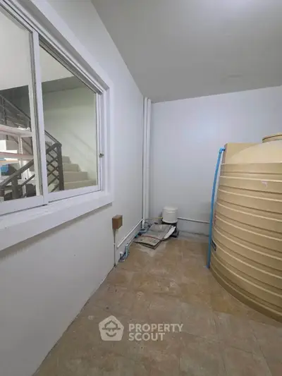 Spacious storage area with large water tank and tiled flooring.