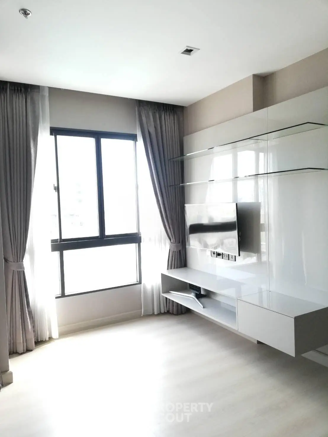 Modern living room with sleek TV unit and large window for natural light.
