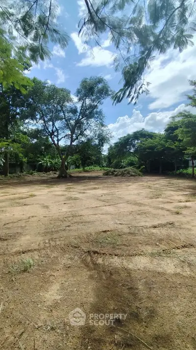 Expansive plot of land with lush greenery and clear blue sky, perfect for development opportunities.