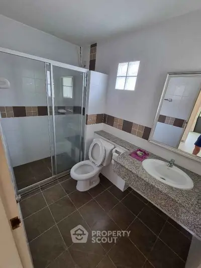 Modern bathroom with glass shower, granite countertop, and tiled floor in a stylish home.