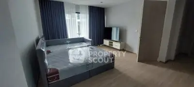 Spacious bedroom with modern furnishings and large window for natural light.