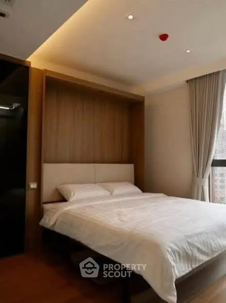 Modern bedroom with cozy lighting and large window for natural light.