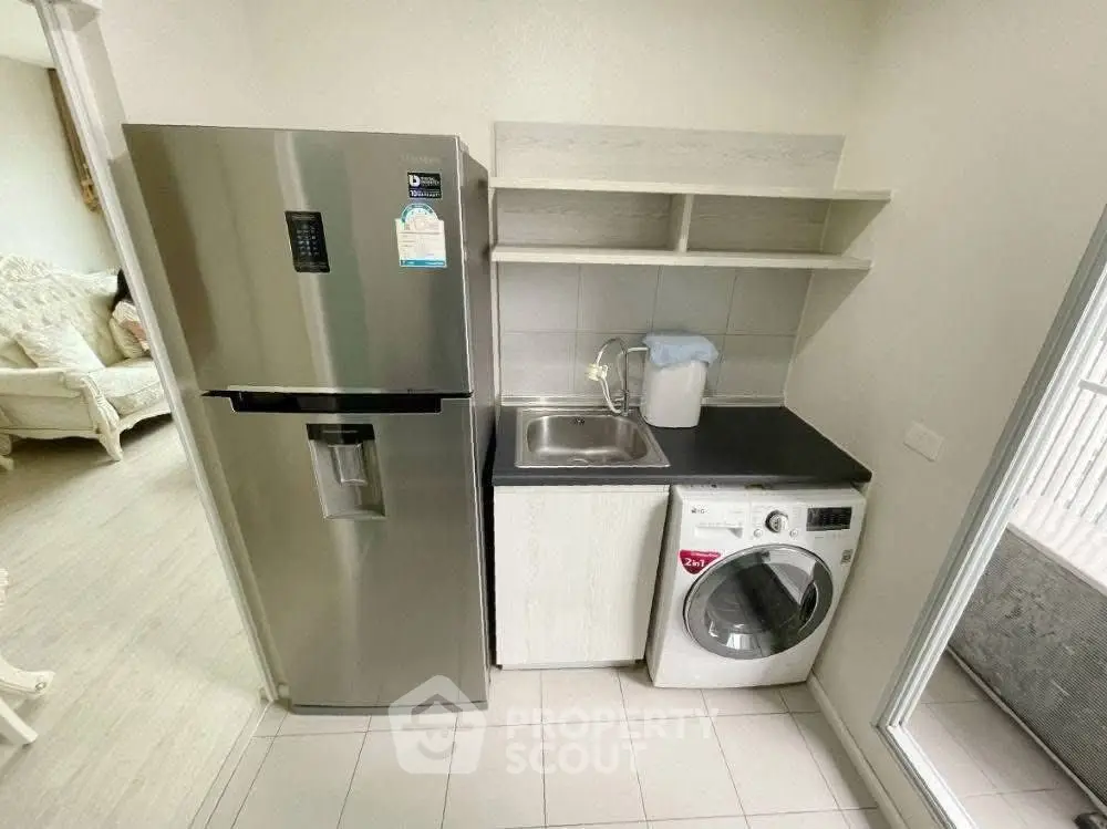 Modern kitchen with stainless steel fridge and washing machine, featuring sleek cabinetry and a compact design.