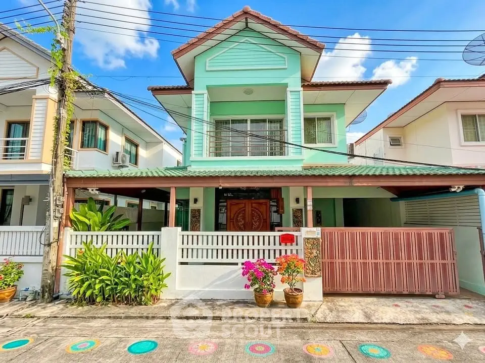 Charming two-story house with green facade and spacious front yard in a serene neighborhood.