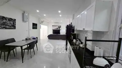 Modern open-plan living room and kitchen with sleek design and bright lighting.
