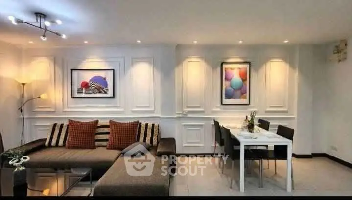 Stylish living room with modern decor and dining area, featuring elegant wall art and cozy lighting.