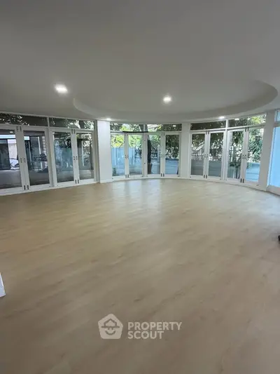 Spacious circular living room with large windows and wooden flooring