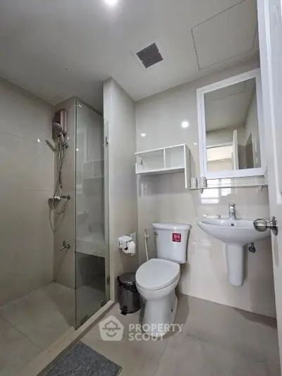 Modern bathroom with glass shower and sleek fixtures in contemporary apartment.