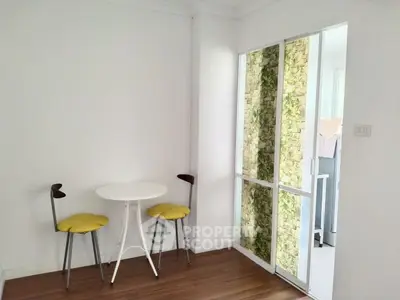 Charming small dining area with modern chairs and table, featuring a unique sliding door with a nature-inspired design.
