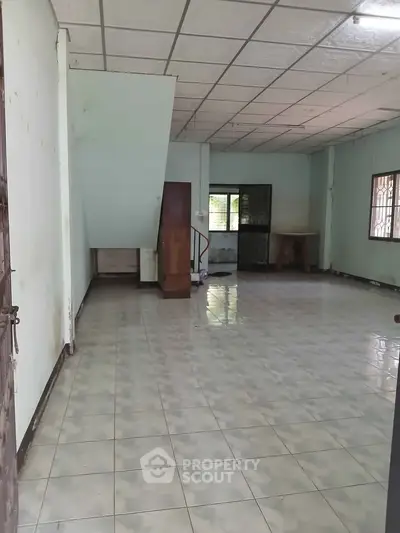 Spacious interior with tiled flooring and staircase, ideal for customization.