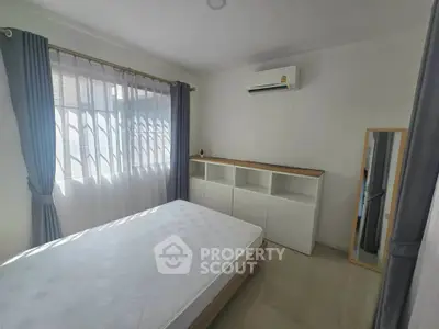 Bright bedroom with large window, air conditioning, and modern furniture, perfect for comfortable living.