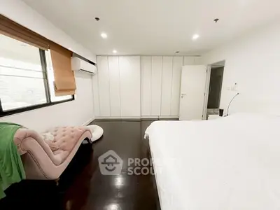 Spacious modern bedroom with sleek dark flooring and elegant furnishings.