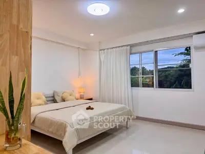 Bright and cozy bedroom with large window and modern decor, perfect for relaxation.