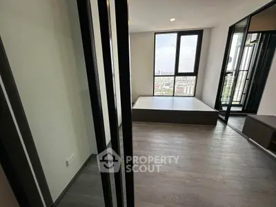 Spacious and modern bedroom with large windows offering ample natural light and a view, featuring elegant wood flooring and a neutral color palette.