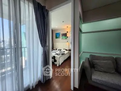 Modern bedroom with balcony and cozy seating area, featuring elegant decor and natural light.