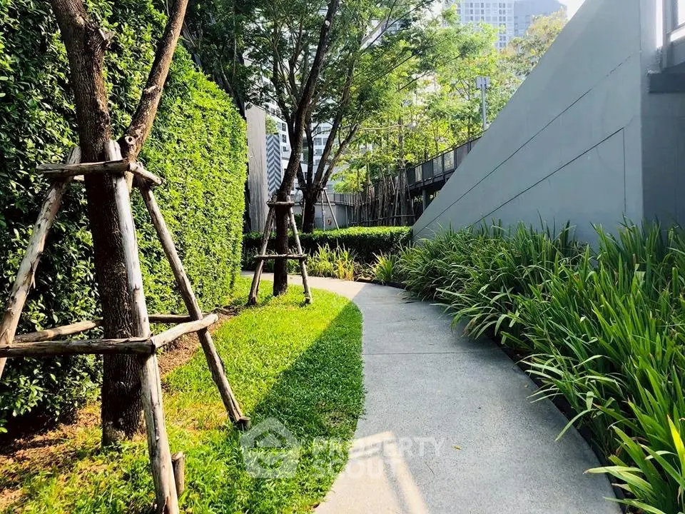 Lush garden pathway in modern residential complex with vibrant greenery and serene ambiance.