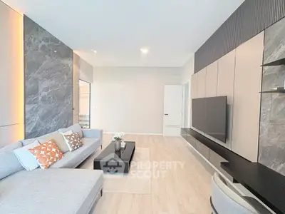 Modern living room with sleek design, featuring a large sofa, wall-mounted TV, and elegant decor.