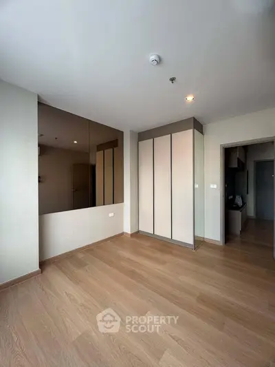 Spacious modern bedroom with wooden flooring and built-in wardrobe in a stylish apartment.