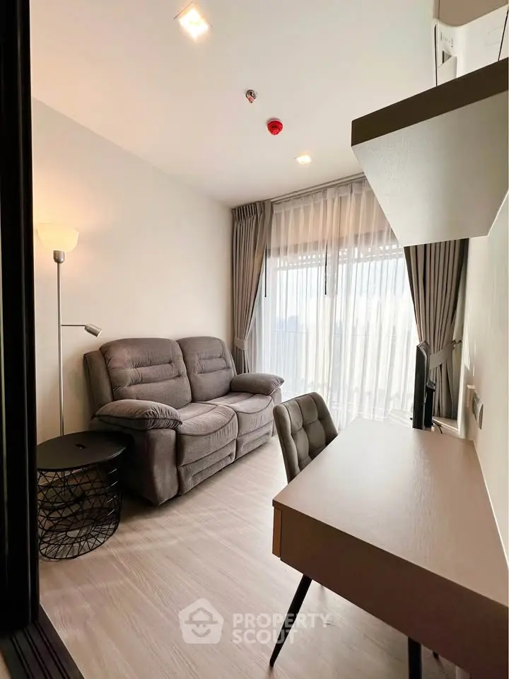 Modern living room with cozy sofa and work desk, featuring floor-to-ceiling windows and elegant curtains.