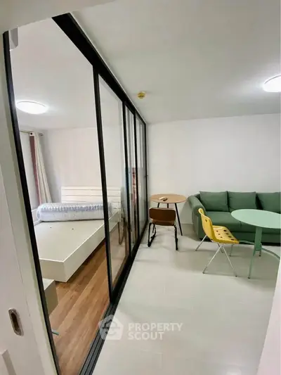 Modern studio apartment with glass partition, cozy living area, and stylish furniture.