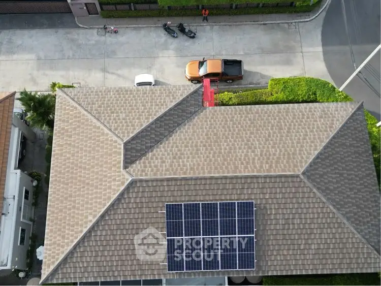 Aerial view of house with solar panels on roof in suburban neighborhood.