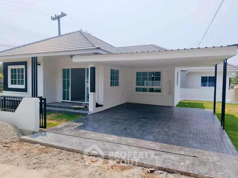 Modern single-story house with spacious driveway and contemporary design.