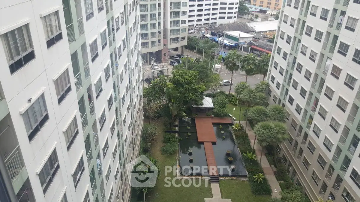 Stunning aerial view of modern apartment complex with lush garden and water feature.