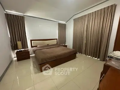 Spacious bedroom with modern furnishings and large windows for natural light.