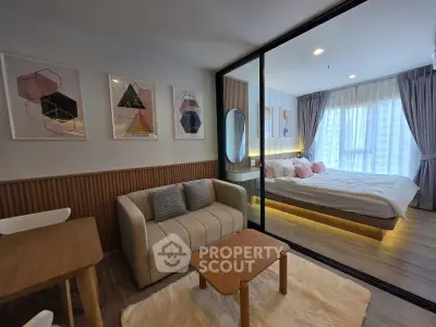 Modern studio apartment with stylish decor, featuring a cozy living area and a comfortable bedroom separated by glass.