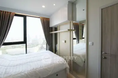 Modern bedroom with large window and city view, featuring sleek design and ample natural light.