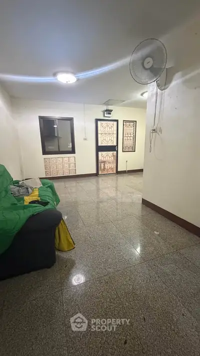 Spacious living room with tiled flooring and ceiling fan, ideal for cozy gatherings.