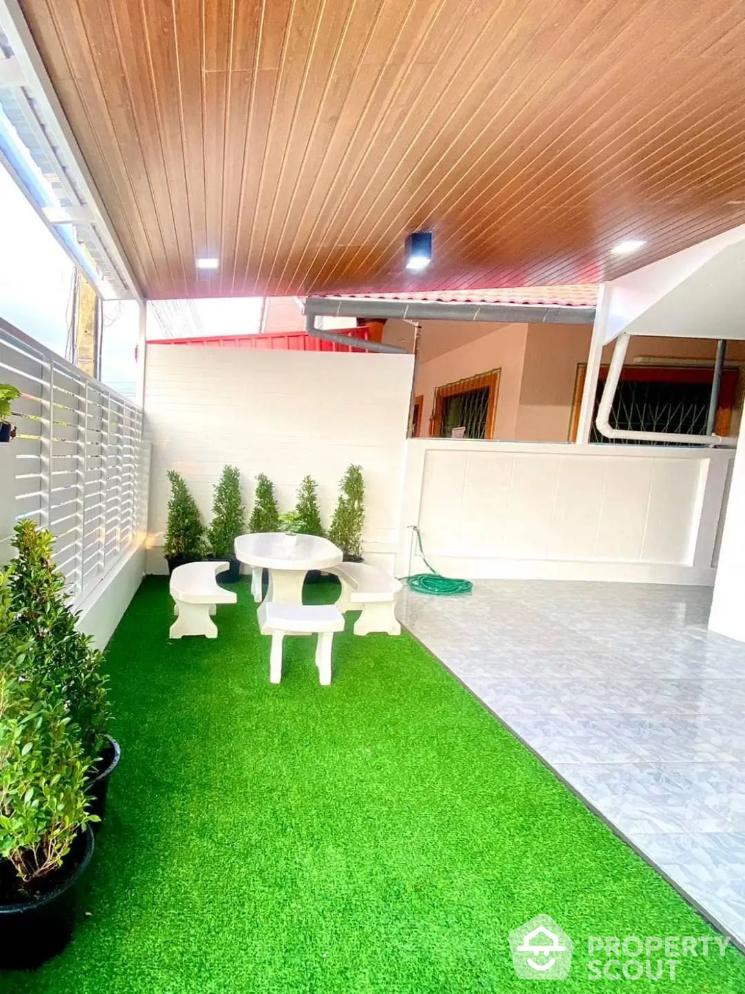 Charming outdoor patio with vibrant artificial grass, cozy seating area, and elegant wooden ceiling, perfect for relaxation and entertainment.