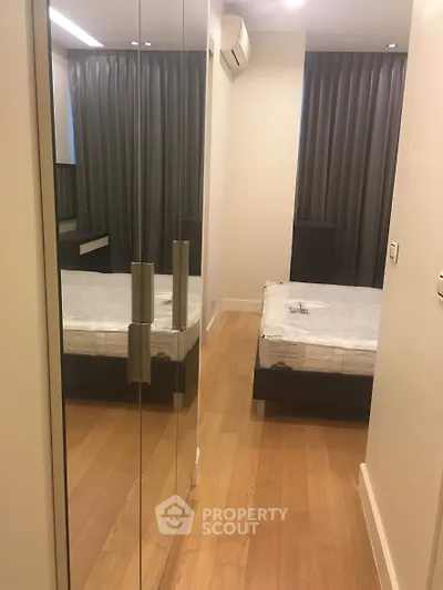 Modern bedroom with mirrored closet and wooden flooring in a cozy apartment.