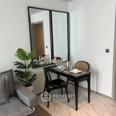 Chic dining nook with elegant black table, stylish chairs, and decorative mirror in modern apartment.