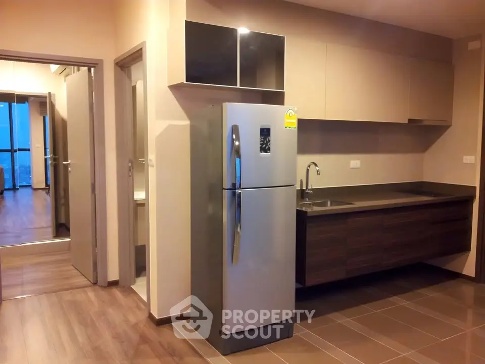 Modern kitchen with sleek cabinetry and stainless steel fridge in a contemporary apartment.