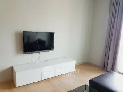 Minimalist living room with wall-mounted TV and sleek white cabinet.