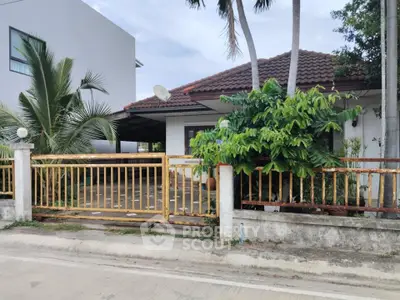 Charming single-story house with lush greenery and gated entrance