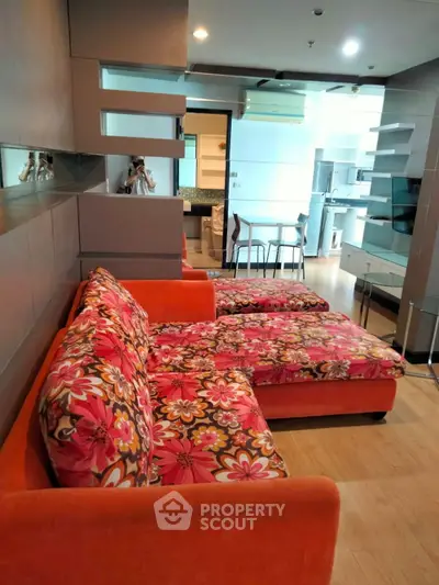 Stylish living room with vibrant floral sofa and modern open kitchen layout
