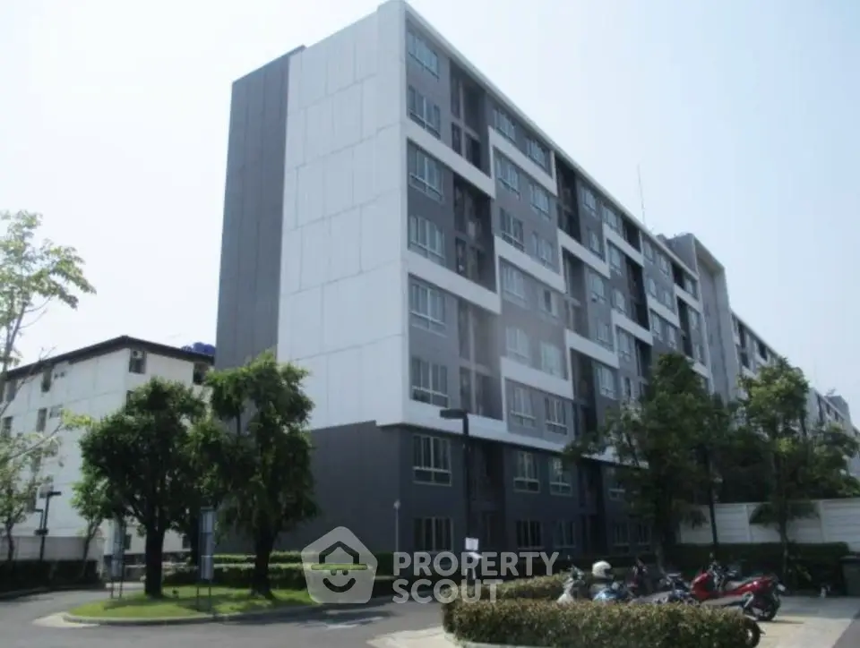 Modern apartment building with lush greenery and ample parking space