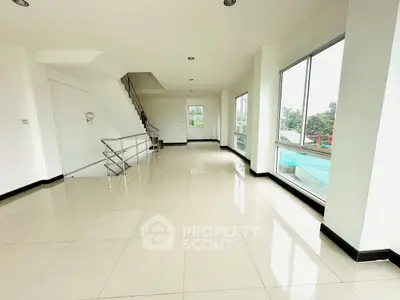 Spacious modern interior with large windows and sleek staircase, perfect for open living.