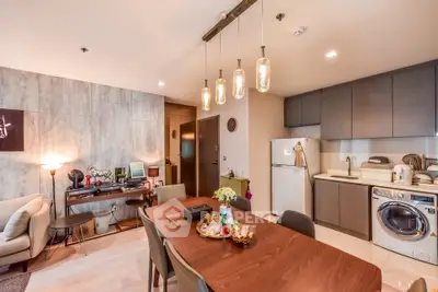 Modern open-plan living room with stylish kitchen and dining area, featuring contemporary lighting and appliances.